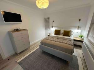 Premium executive Apartment in Dunfermline في دنفرملاين: غرفة نوم بسرير وخزانة وتلفزيون