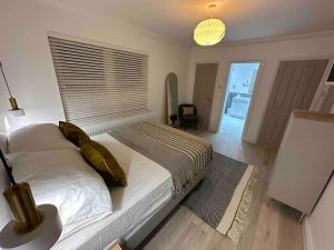 ダンファームリンにあるPremium executive Apartment in Dunfermlineのベッドルーム1室(白いシーツと金の枕が備わるベッド1台付)