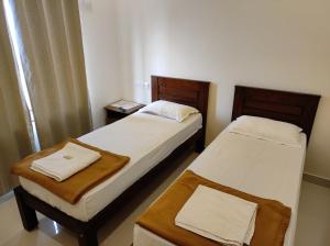 twee bedden in een kleine kamer met rokken bij MITRA HOTELS in Mysore