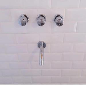 una ducha con tres luces en una pared blanca en A Morriña en Santa Lucía
