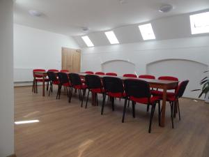 a conference room with a table and red chairs at Penzion Bednářův dvůr in Bohušice