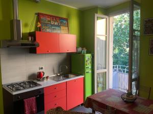 a kitchen with red cabinets and a green refrigerator at Principessa Como close to the lake in Como