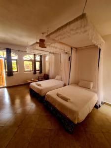 a bedroom with two beds with white sheets and windows at GKAT Resort in Mbarara