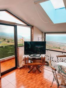 a living room with a large television and large windows at Sun-soaked apt w patio, balcony & garden - Aguilas in La Orotava