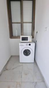 uma máquina de lavar roupa com um micro-ondas em cima em New Stylish Apartment with Balcony Close to Tel Aviv em Bene Beraq