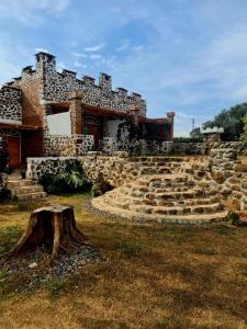 una casa de piedra con un tronco de árbol delante de ella en GKAT Resort en Mbarara