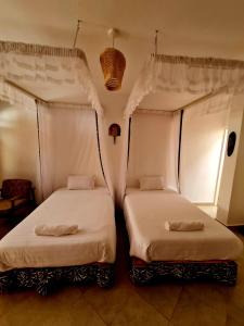 2 letti posti uno accanto all'altro in una stanza di GKAT Resort a Mbarara