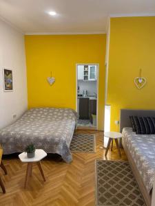 a room with two beds and a yellow wall at IGNIM Apartment in Subotica