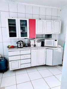a kitchen with white cabinets and white appliances at Casa aconchegante. in Campo Grande