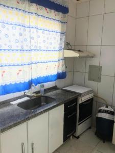 uma pequena cozinha com um lavatório e uma janela em Casa aconchegante. em Campo Grande