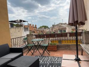 eine Terrasse mit einem Sonnenschirm und einem Tisch auf dem Balkon in der Unterkunft UNE TERRASSE SUR LES TOITS in Aix-en-Provence