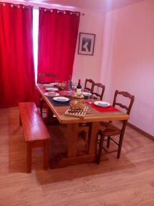 a dining room table with chairs and a red curtain at Champeix, maison confort 6 personnes in Champeix