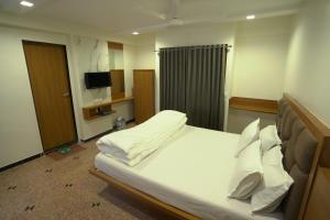 a bedroom with a large bed with white sheets and pillows at Hotel Shertown in Ahmedabad