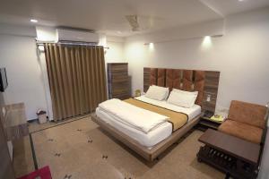 um quarto com uma cama grande e uma cadeira em Hotel Shertown em Ahmedabad