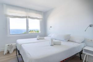 a white bedroom with two beds and a window at Boutique Ocean Terrace Luxury II - SSHOUSING in Igueldo