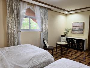 a bedroom with a bed and a desk and a window at CAMPJOHNHAY Forest Estate in Baguio