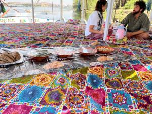 a table topped with colorful fabrics and bowls of food at Freedom Boat in Naj‘ al ‘Amrāb
