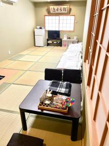 a living room with a table and a bed at Wafu Ryokan Uehonmachi in Osaka