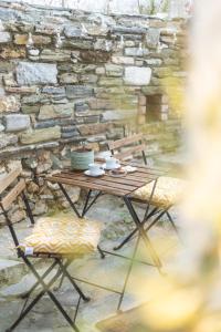 a wooden table and two chairs and a stone wall at Bardis Hidden Gem in Volos