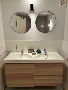 La salle de bains est pourvue de 2 lavabos et de 2 miroirs. dans l'établissement Historische Wohnung am Jenischpark, à Hambourg