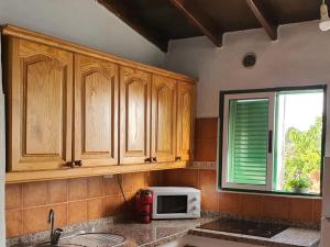 cocina con armarios de madera y microondas en la encimera en Rinconcito Rural con encanto en Las Hayas, en Acardece