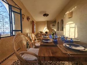 una sala da pranzo con tavolo, sedie e finestra di Dar el janoub a Essaouira