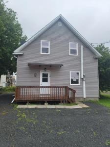 a house with a large porch with a deck at Cute apartment close to highway in Edmundston