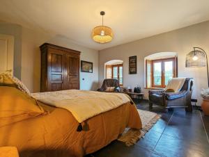 a bedroom with a large bed and two chairs at Le clos des pierres rouges in Saint-Privat-dʼAllier