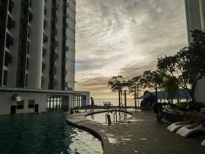 a swimming pool in a building with people sitting around it at Comic Homestay @ The Shore in Kota Kinabalu