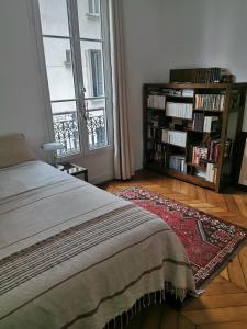 a bedroom with a bed and a book shelf with books at Home sweet home in Paris