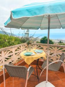 勞羅塔瓦的住宿－Sun-soaked apt w patio, balcony & garden - Aguilas，阳台的遮阳伞下的桌椅