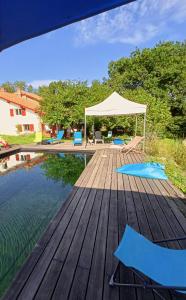a wooden deck next to a pool with a tent at Chambres Maison Labourdasse in Saint-Martin-de-Hinx
