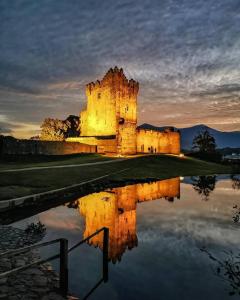 an old castle with its reflection in the water at Kilarney cottage in Killarney