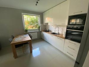a kitchen with white cabinets and a table and a window at Rose Apartament in Brwinów