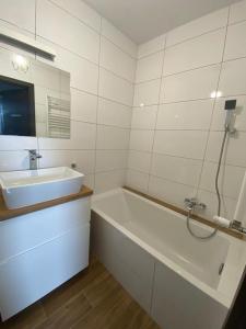 La salle de bains est pourvue d'un lavabo et d'une baignoire. dans l'établissement Rose Apartament, à Brwinów