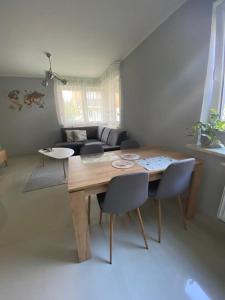 - un salon avec une table et des chaises en bois dans l'établissement Rose Apartament, à Brwinów