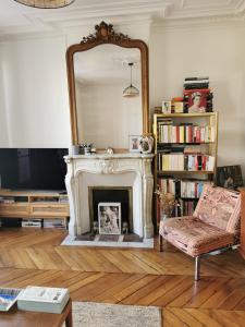 a living room with a fireplace and a mirror at Home sweet home in Paris