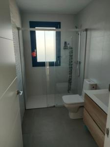 een witte badkamer met een douche en een toilet bij relax al pie de la alfaguara in Alfacar