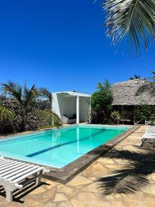 a swimming pool with two chairs and a house at Manasha Apartment 1 in Watamu