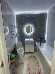 een badkamer met een bad, een toilet en een wastafel bij 1 комнатная квартира Аппартаменты ЖК Aspan city in Alma-Ata