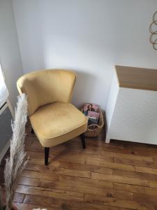 Appartement cosy في Saint-Martin-Longueau: كرسي أصفر في غرفة مع أرضية خشبية