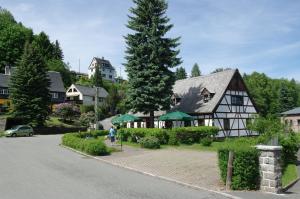 a woman walking down a street in front of a house at Wirtschaft & Pension Zum Huthaus in Schneeberg