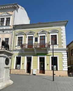 a yellow building with a statue in front of it at M Central Apartments in Cluj-Napoca