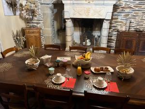a dining room table with food and a fireplace at Le Clos Saint Fiacre in Carentoir