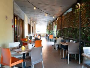 une salle à manger avec des tables, des chaises et des plantes dans l'établissement Hotel Garni Rosmari, à Brenzone