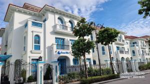 un bâtiment blanc avec des fenêtres bleues et une clôture dans l'établissement OCEAN VILLA - Sun Grand Feria Hạ Long, à Hạ Long