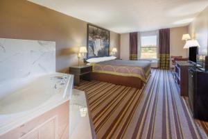 a hotel room with a bed and a bath tub at Super 8 by Wyndham La Grange KY in La Grange
