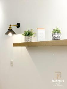 a shelf with plants and a light on a wall at Blumeen Lite 1 - Comfortable Budget Home 3BR in Kuala Terengganu