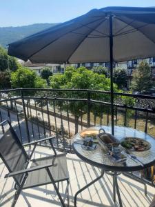 una mesa y sillas con una sombrilla en el balcón en Comfort Hotel Prizren, en Prizren