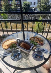 a glass table with plates of food on a balcony at Comfort Hotel Prizren in Prizren